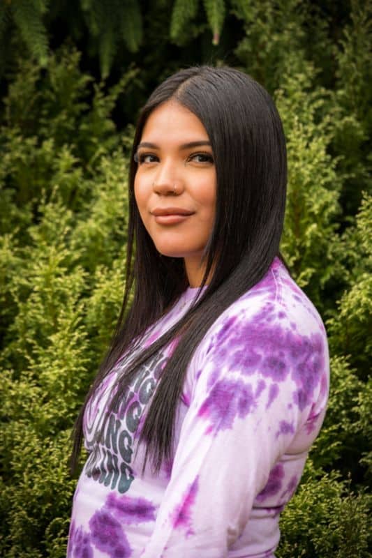 a woman with long hair in front of bushes