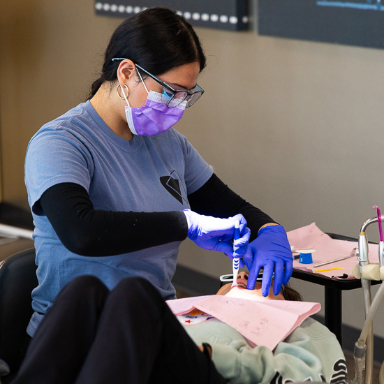 Dental Assistant cleaning a childs teeth with a tooth brush