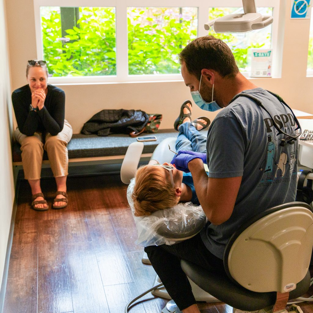 Mother watching child receive dental treatment