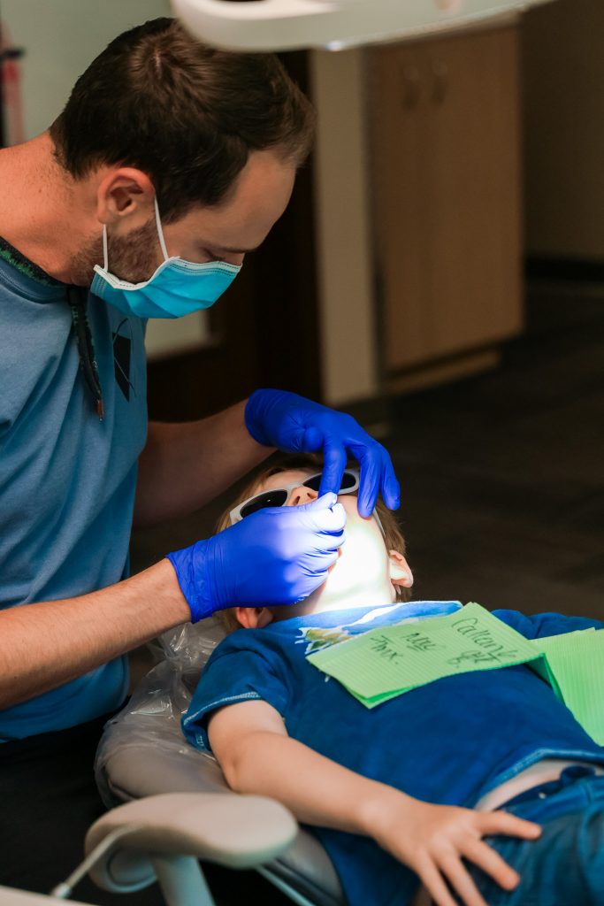 Pediatric dentist giving a child dental treatment in a dental office